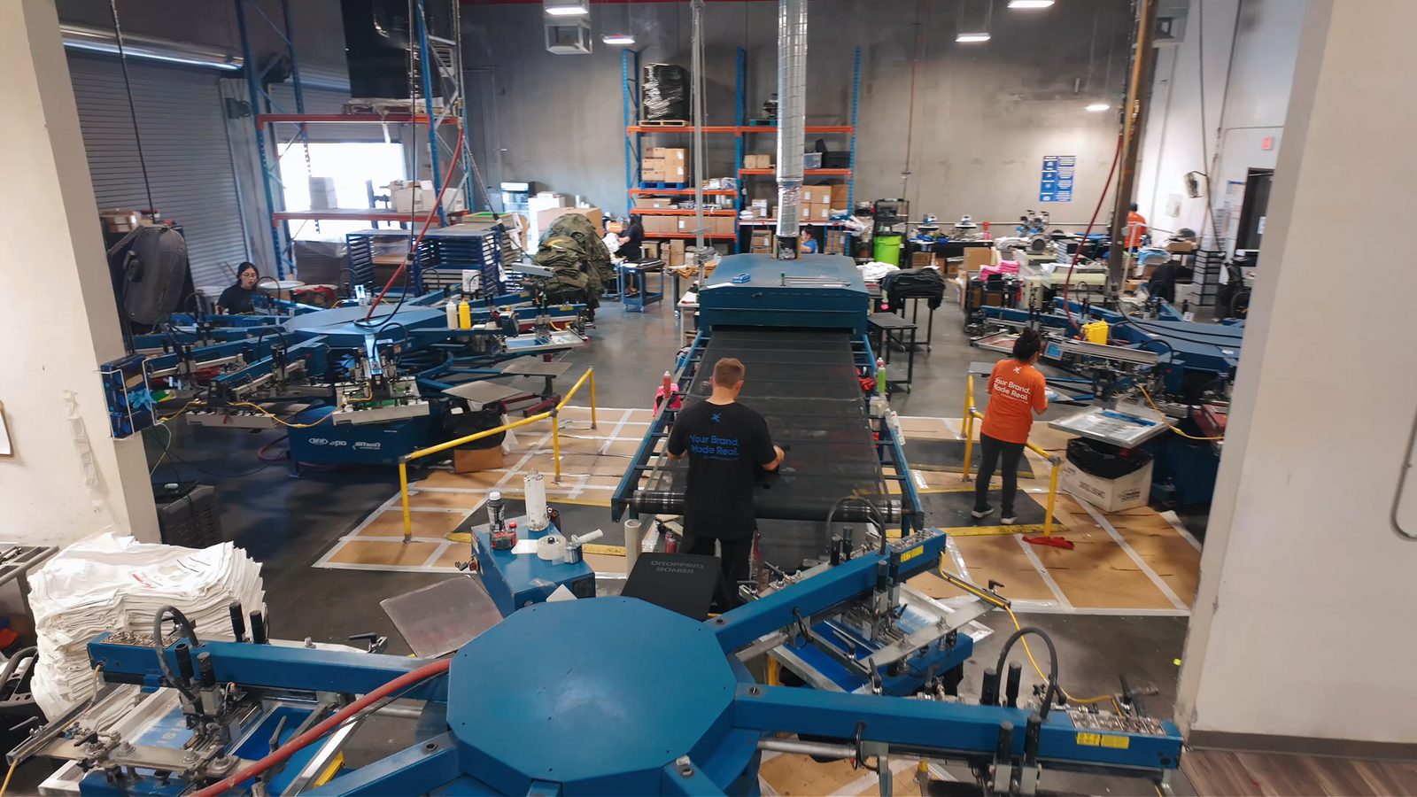 Alive Print Shop production floor in North Las Vegas with automatic screen printing presses and a conveyor dryer.